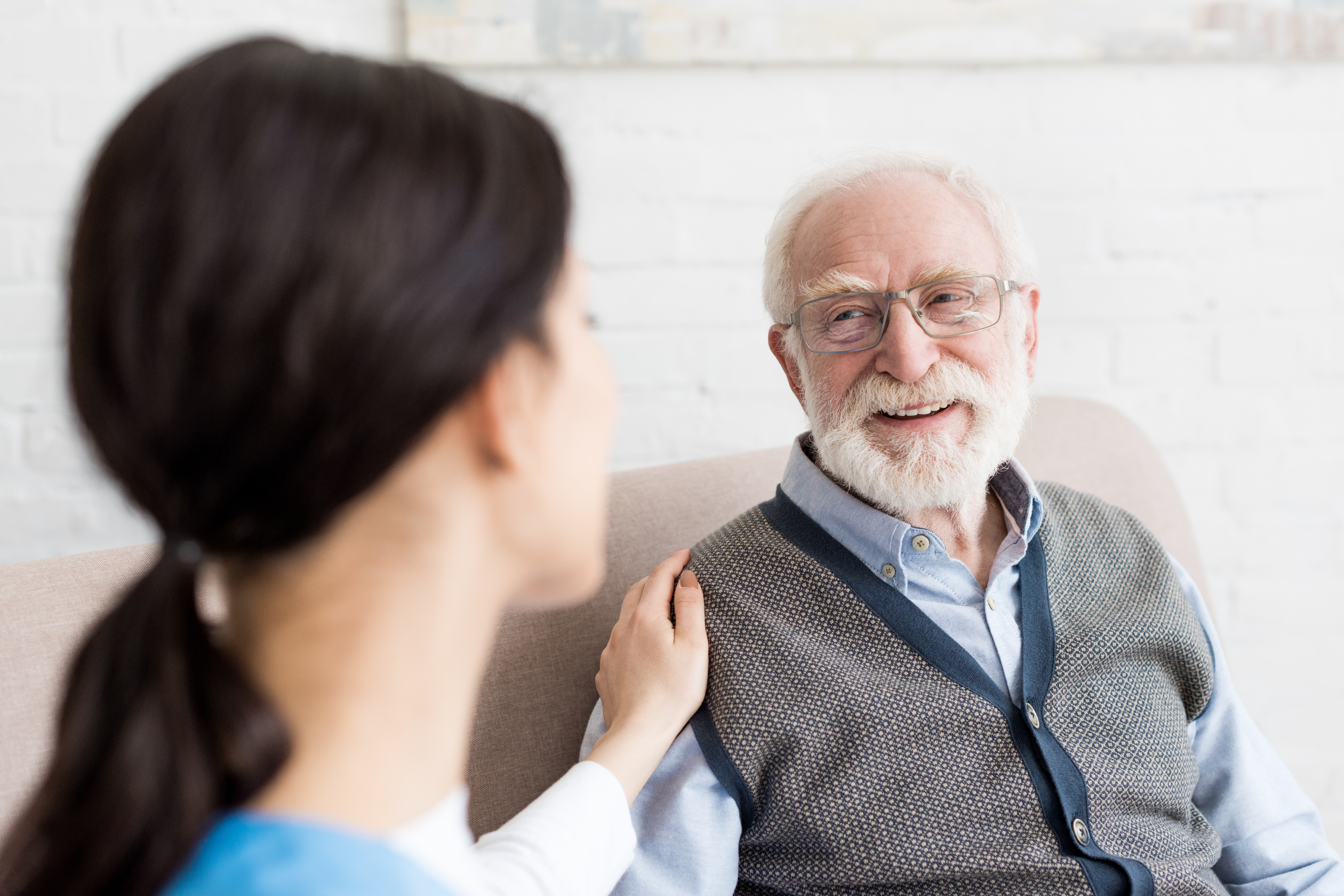 Selective focus of smiling grey haired man looking at nurse